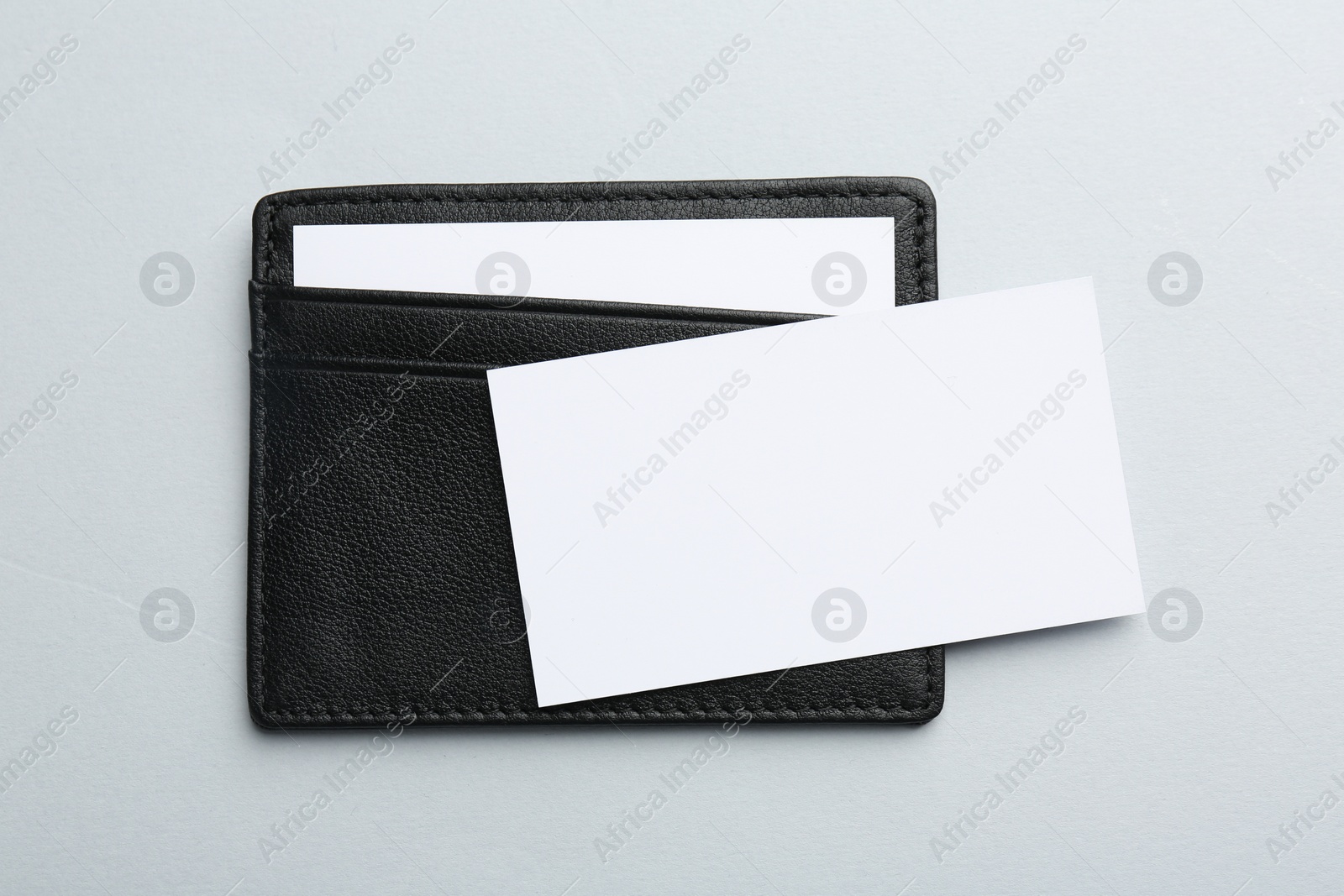 Photo of Leather business card holder with blank cards on light grey background, top view