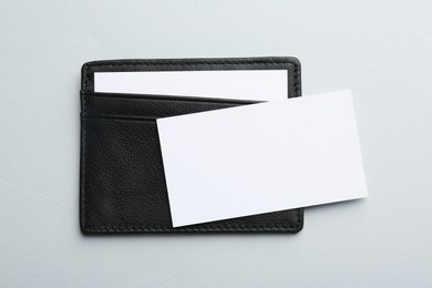 Leather business card holder with blank cards on light grey background, top view