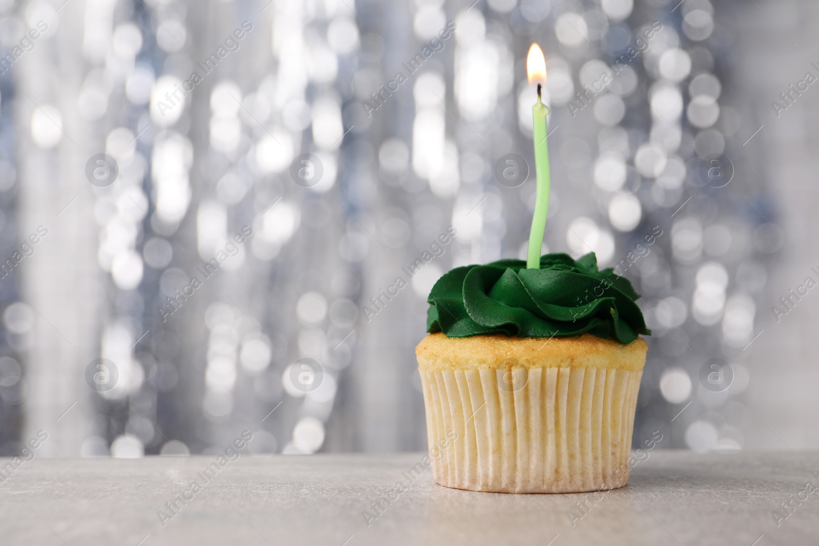 Photo of Delicious cupcake with bright cream and burning candle on grey table, closeup. Space for text