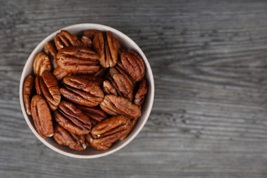 Photo of Tasty pecan nuts on grey wooden table, top view. Space for text