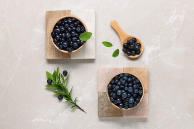 Photo of Tasty fresh bilberries and green leaves on light grey marble table, flat lay