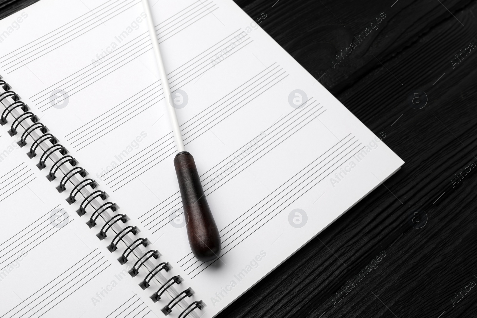 Photo of Conductor's baton and lead sheet on black wooden table