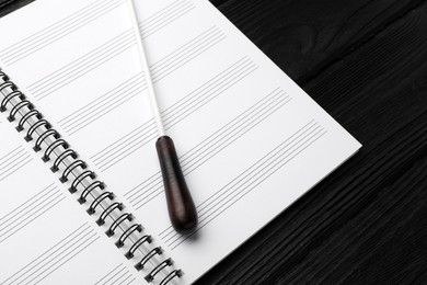 Conductor's baton and lead sheet on black wooden table