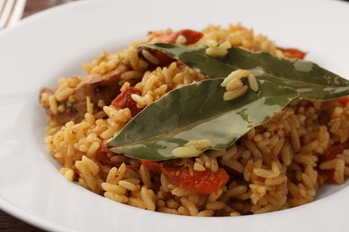 Photo of Delicious pilaf and bay leaves on plate, closeup
