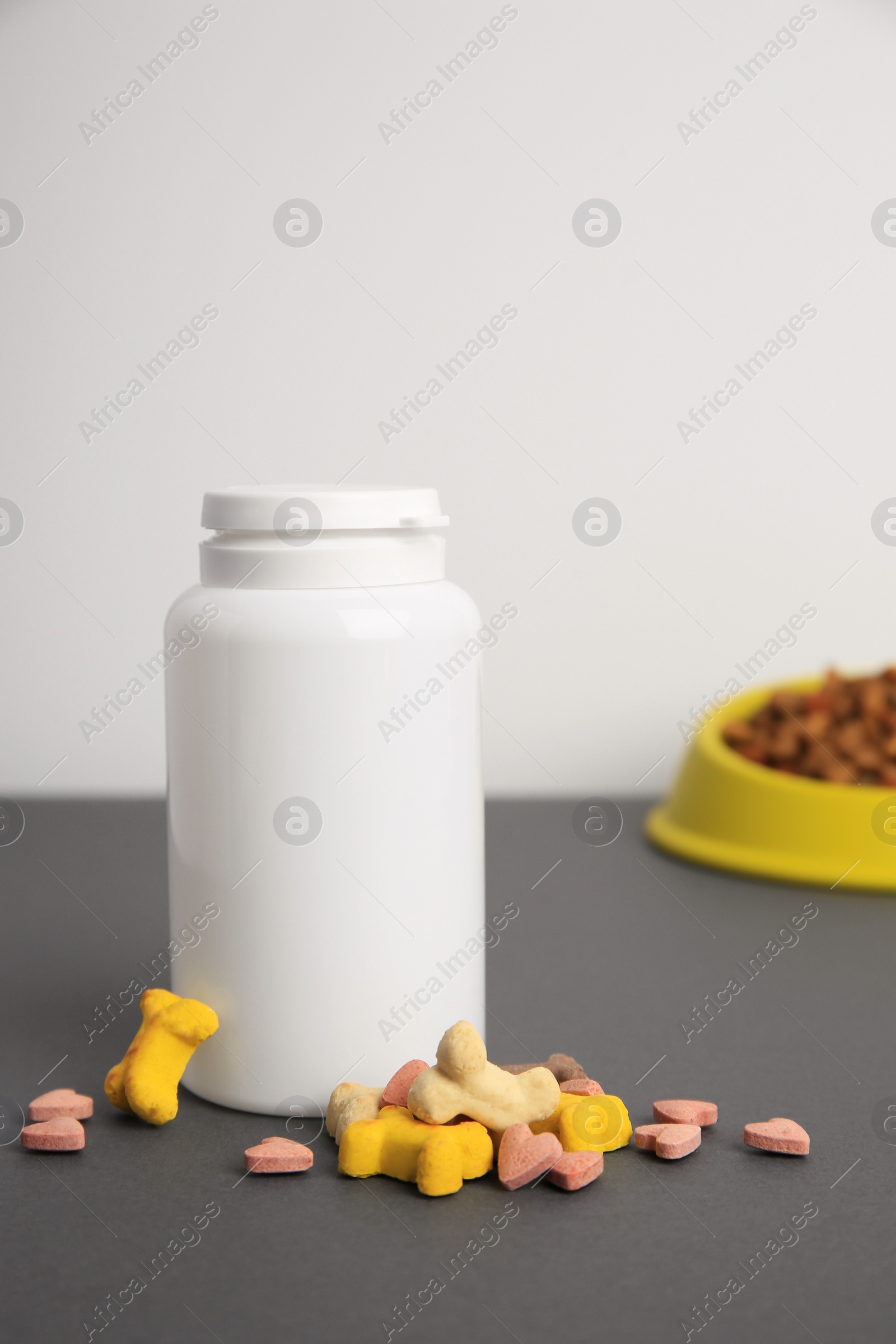 Photo of Bottle with pet vitamins on grey table, closeup