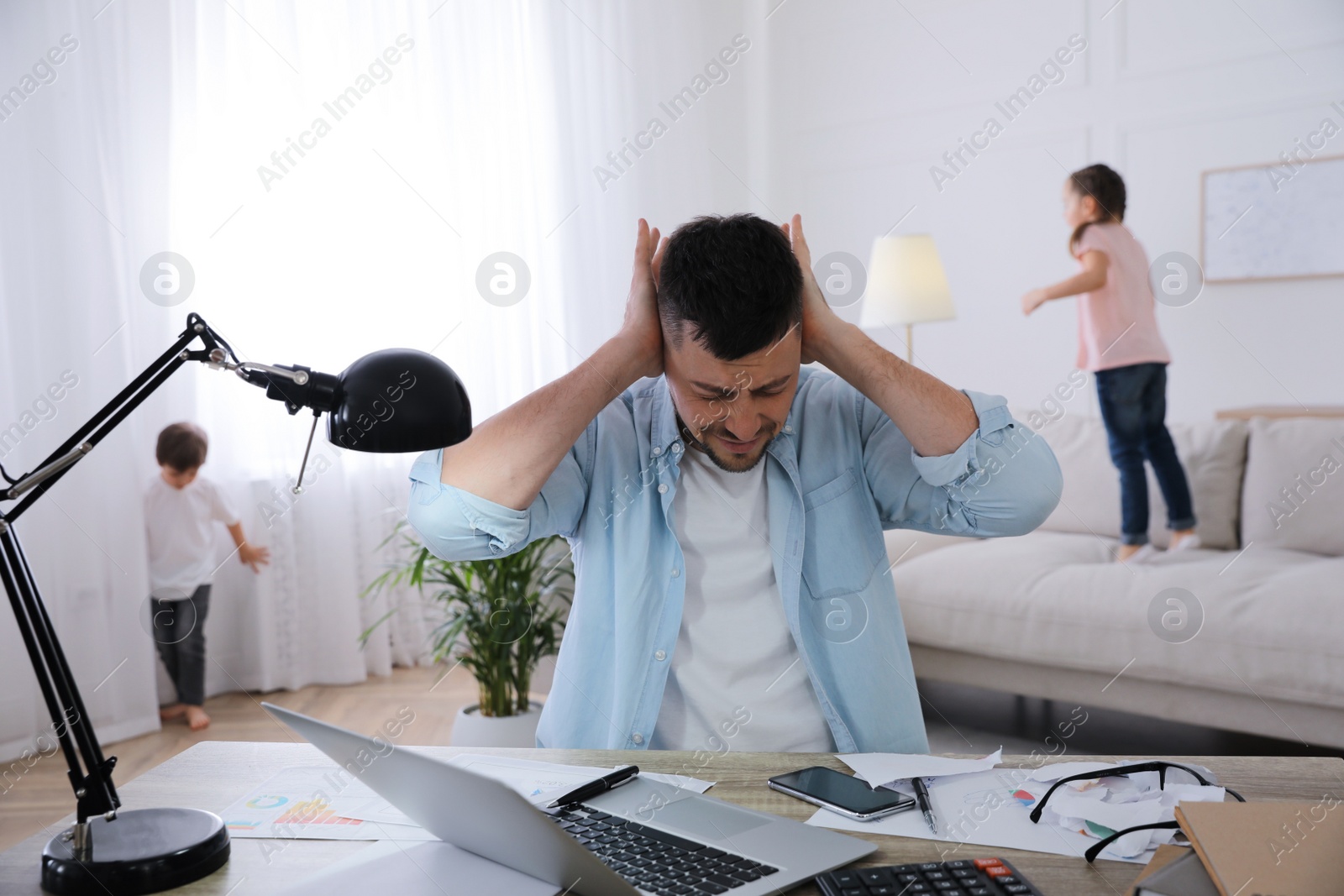 Photo of Overwhelmed man combining parenting and work at home