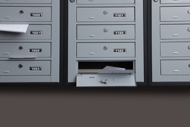 Photo of Grey metal mailboxes with receipts and envelopes indoors