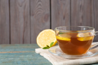 Photo of Tasty lemon tea on light blue wooden table, closeup. Space for text