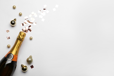 Photo of Flat lay composition with confetti, festive decor and bottle of champagne on light background. Space for text