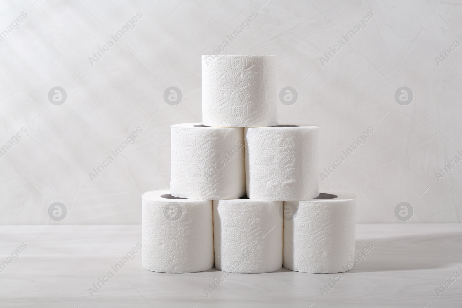 Photo of Pyramid of toilet paper rolls on white wooden table