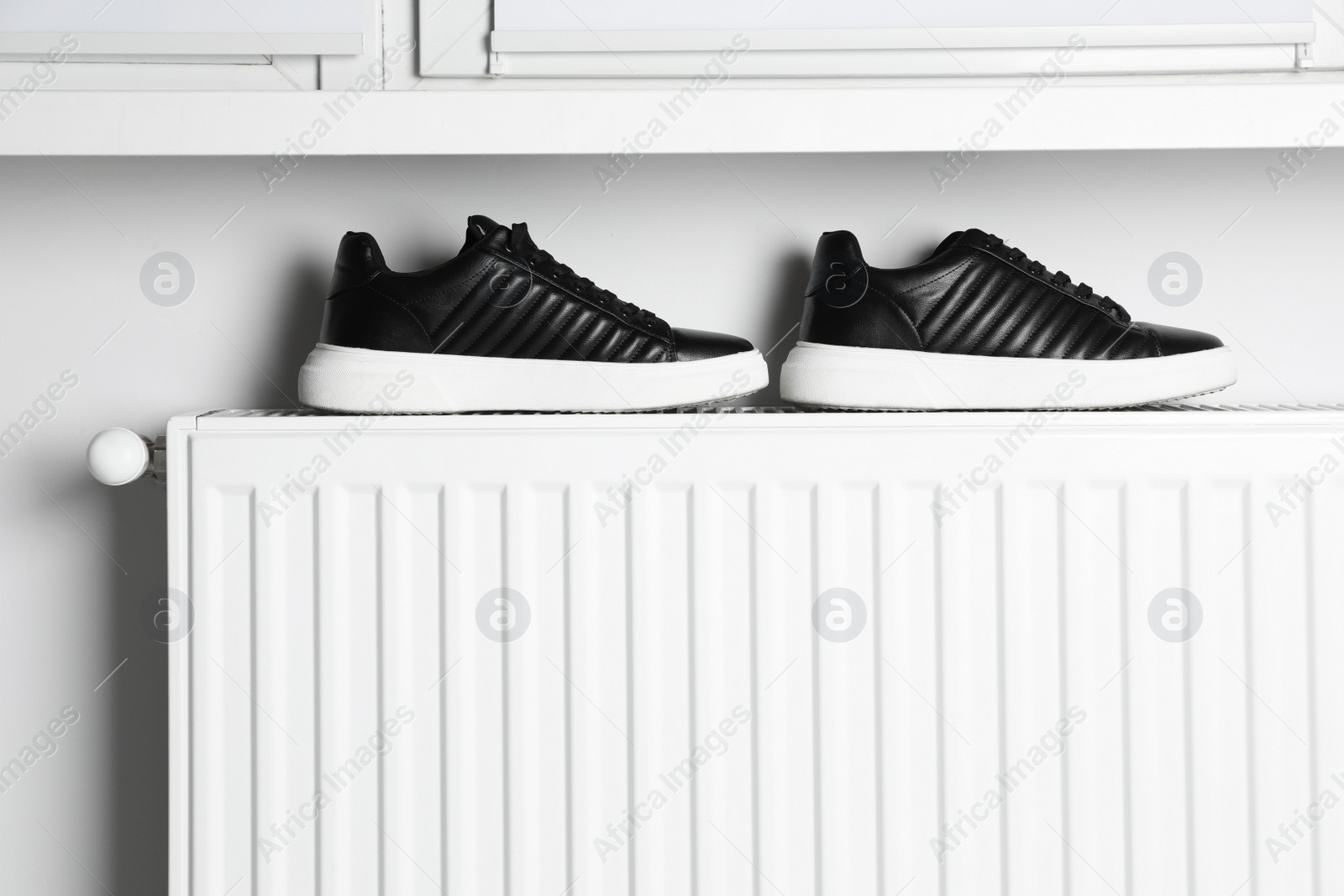 Photo of Black shoes on white radiator in room