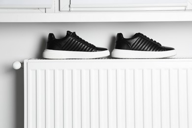 Black shoes on white radiator in room