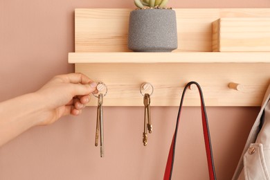 Photo of Woman taking keys from hanger in hallway, closeup