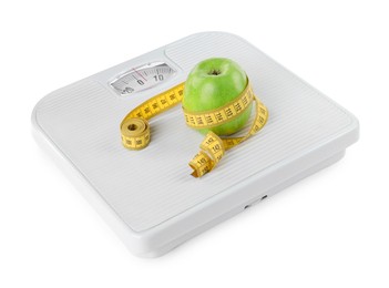 Photo of Weight loss concept. Ripe apple and measuring tape on scales isolated on white