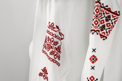 Photo of Beautiful shirts with different embroidery designs on white background, closeup. Ukrainian national clothes
