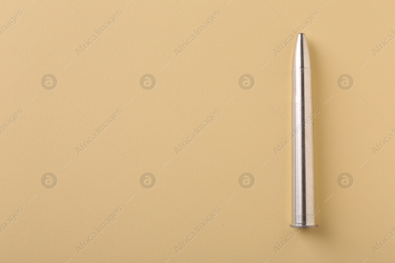 Photo of One metal bullet on yellow background, top view. Space for text