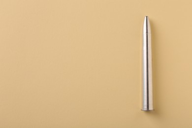 Photo of One metal bullet on yellow background, top view. Space for text