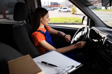 Photo of Courier checking time in car. Delivery service