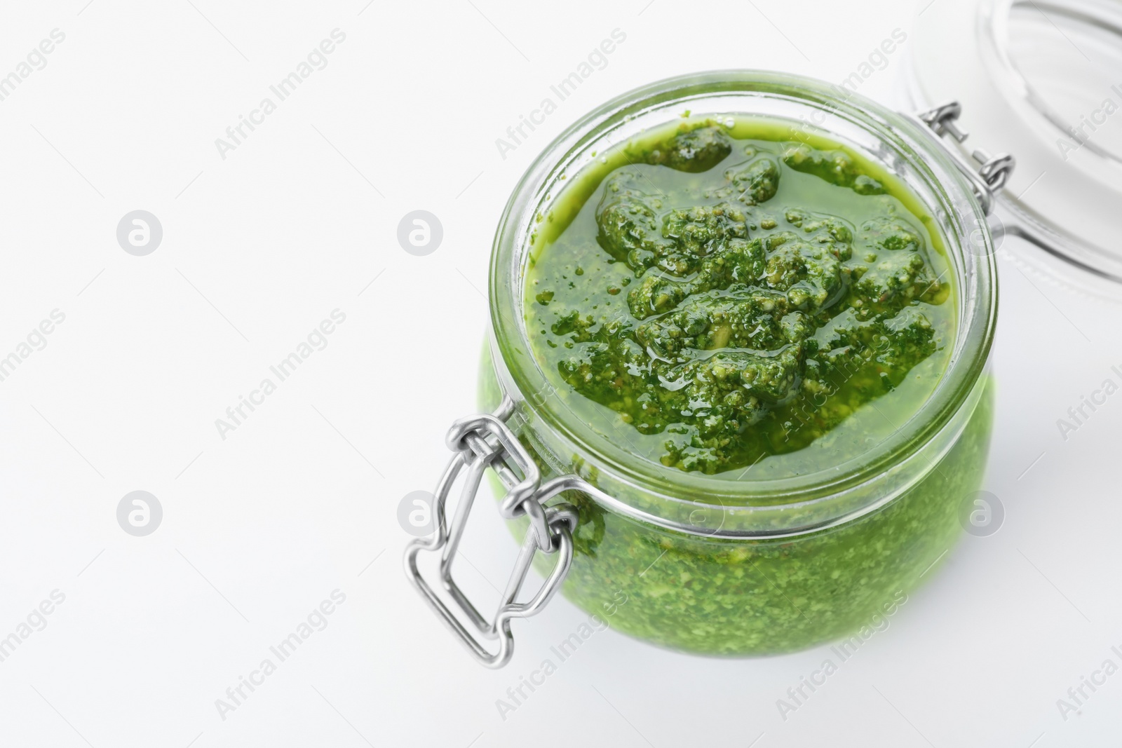 Photo of Homemade basil pesto sauce in glass jar on white background