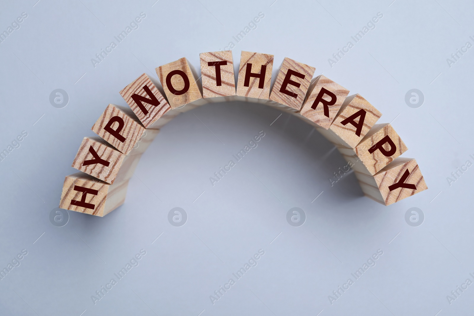 Photo of Wooden blocks with word HYPNOTHERAPY on light background, flat lay