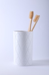 Bamboo toothbrushes in holder on white background