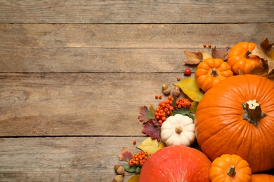 Photo of Flat lay composition with pumpkins and autumn leaves on wooden table. Space for text