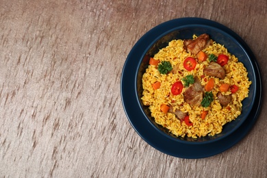 Photo of Plate of rice pilaf and meat on wooden background, top view with space for text