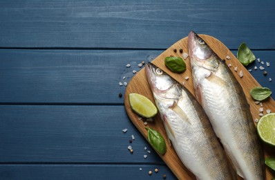 Photo of Fresh raw pike perches and ingredients on blue wooden table, flat lay with space for text. River fish