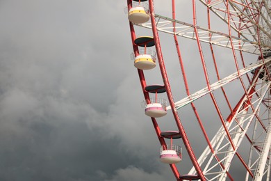 Photo of Beautiful large Ferris wheel against heavy rainy clouds outdoors. Space for text