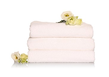 Photo of Folded soft terry towels with beautiful flowers on white background