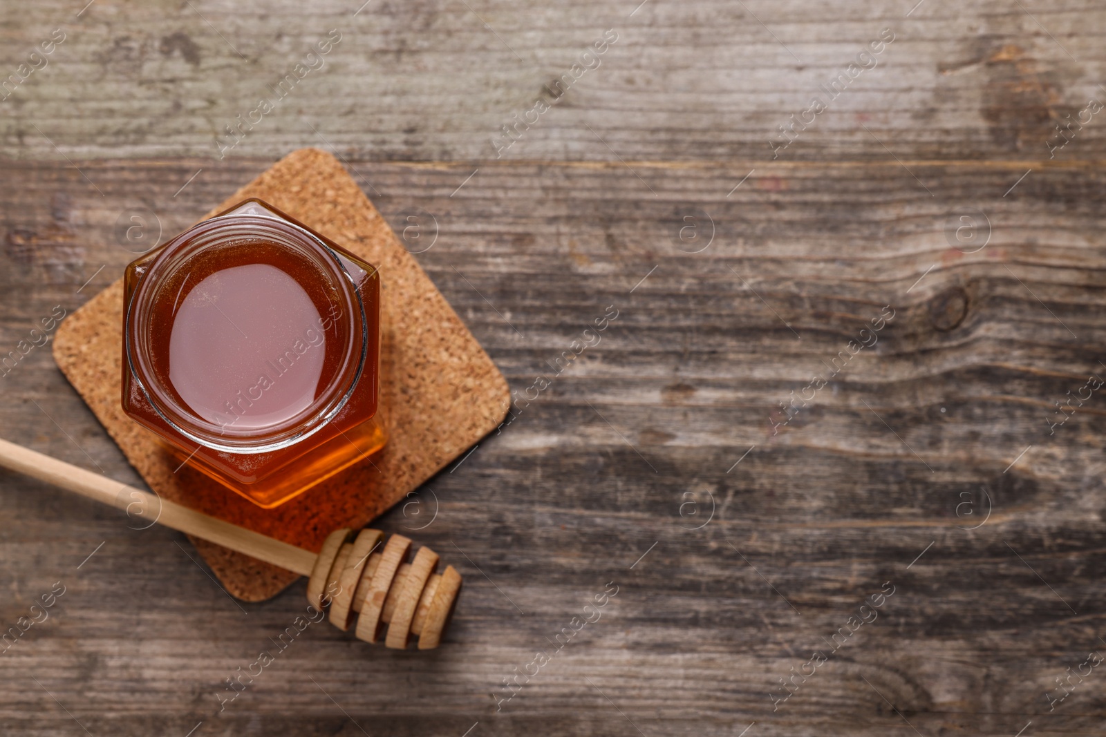 Photo of Sweet honey in jar and dipper on wooden table, top view. Space for text