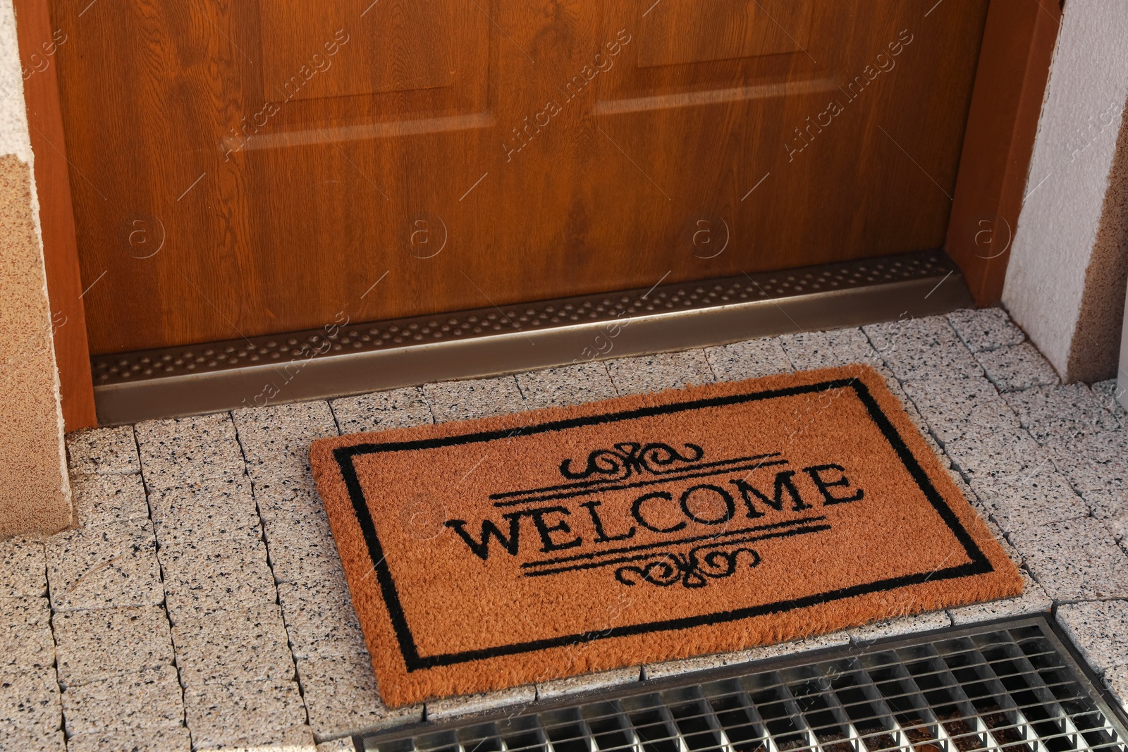 Photo of Door mat with word Welcome on street tiles near entrance