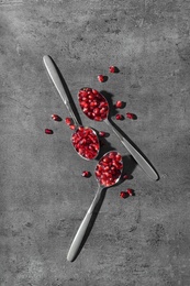 Photo of Flat lay composition with spoons and pomegranate seeds on grey background