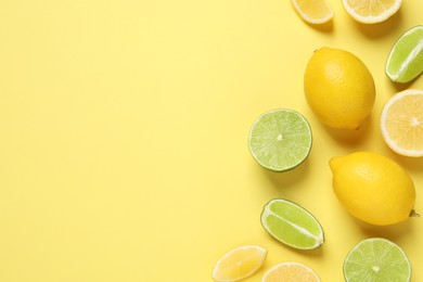 Photo of Fresh ripe lemons and limes on yellow background, flat lay. Space for text