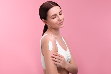 Photo of Beautiful woman with smear of body cream on her shoulder against pink background