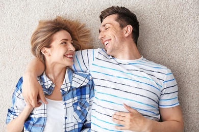 Lovely young couple lying on cozy carpet at home