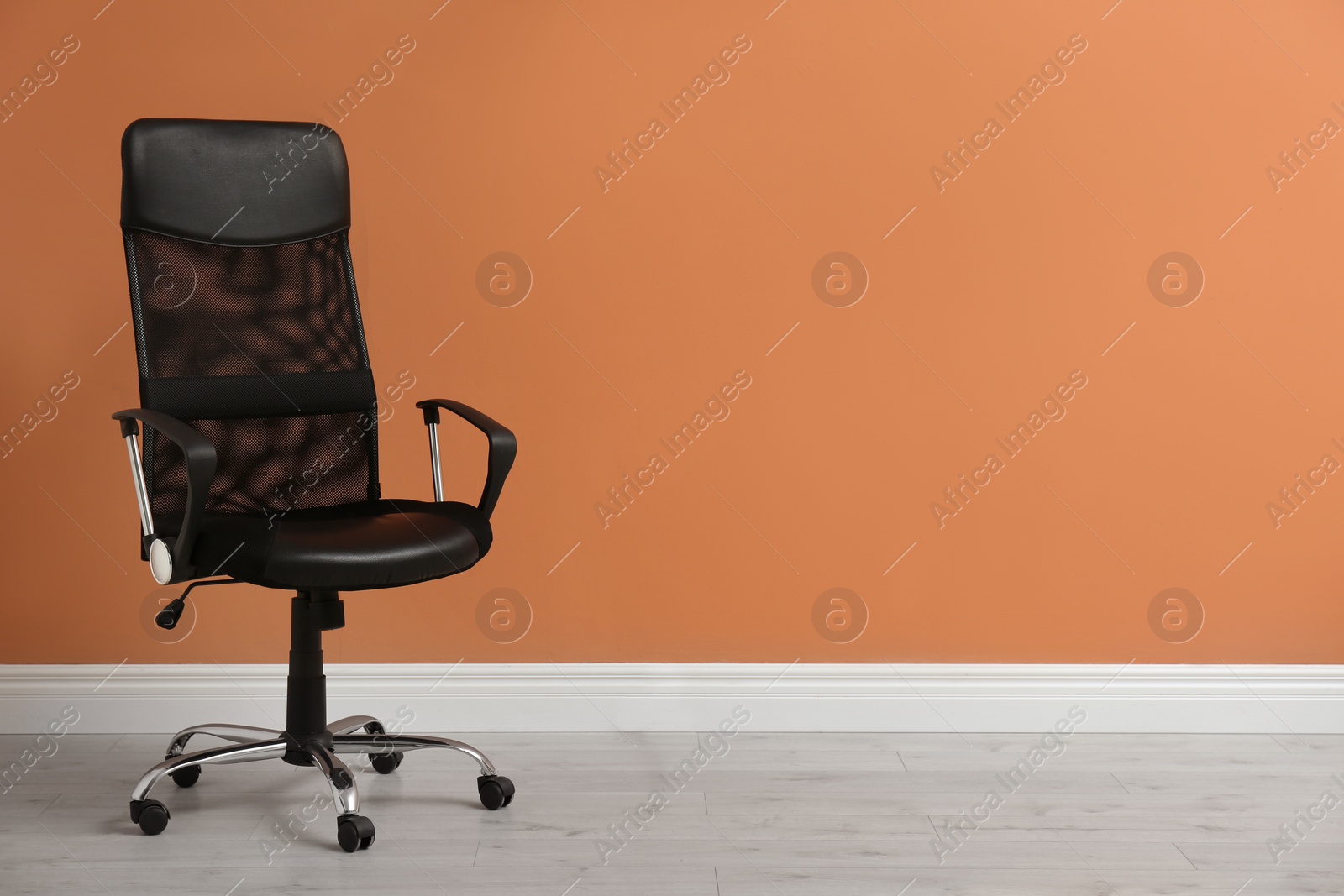 Photo of Modern office chair near orange coral wall indoors. Space for text