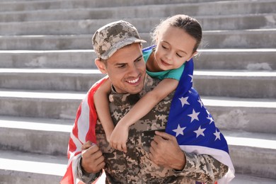 Photo of Soldier with flag of USA and his little daughter outdoors