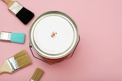 Photo of Bucket of orange paint and brushes on pink background, flat lay. Space for text
