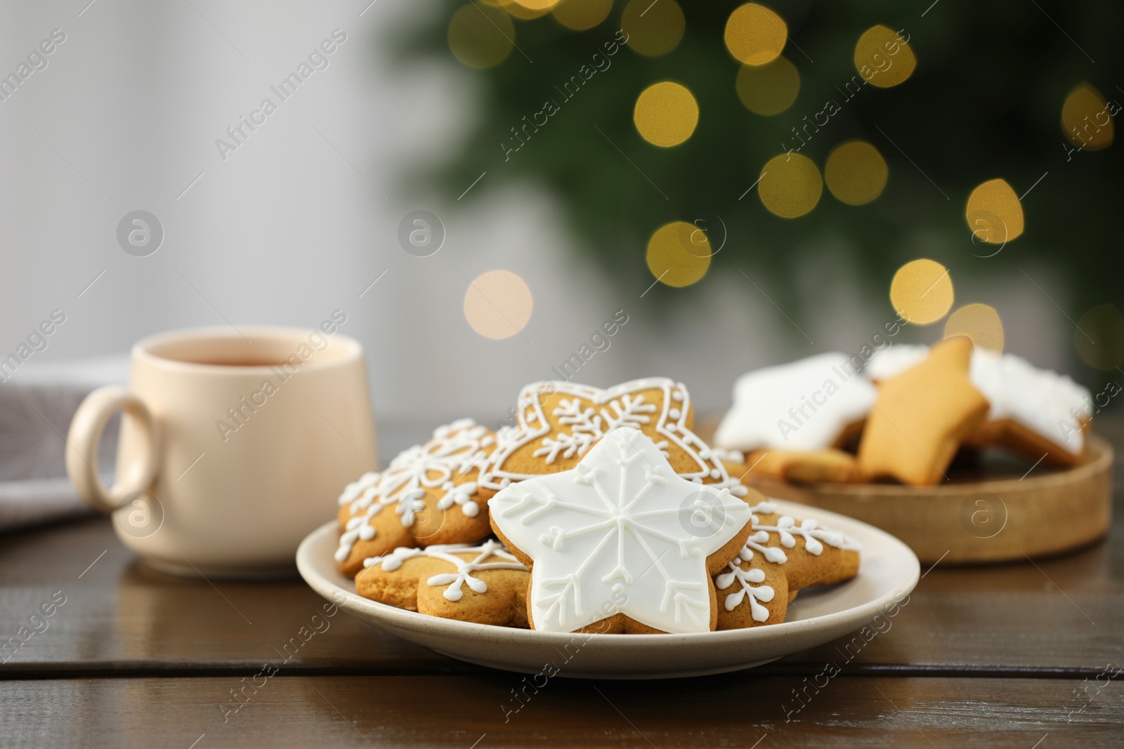 Photo of Decorated cookies and hot drink on wooden against blurred Christmas lights