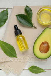 Photo of Essential oil, ripe fresh avocado and leaves on white wooden table, flat lay