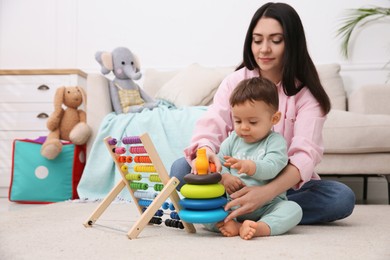 Photo of Cute baby boy playing with mother and toys on floor at home