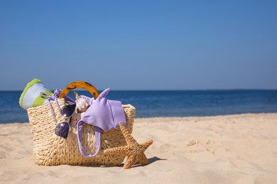 Photo of Bag with beach accessories on seaside. Space for text