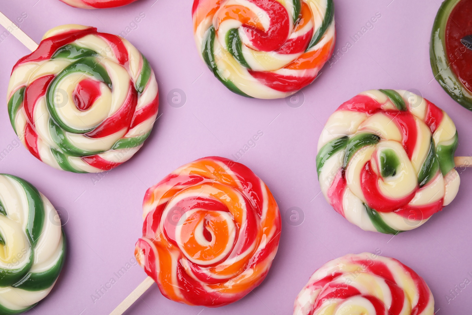 Photo of Many colorful lollipops on violet background, flat lay