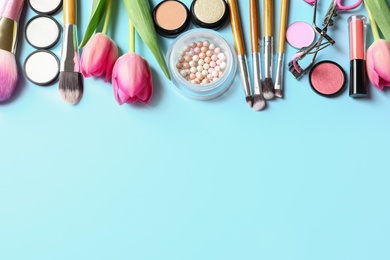 Photo of Makeup products and flowers on color background, flat lay with space for text