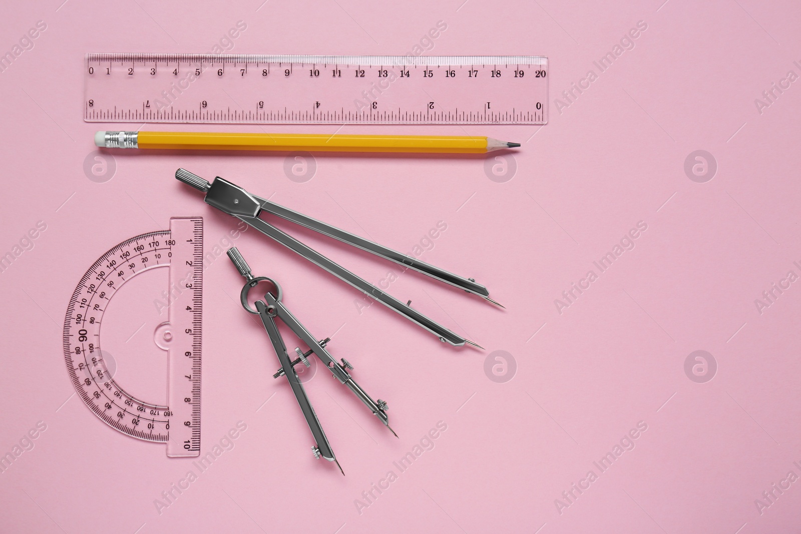 Photo of Different rulers, pencil and compasses on pink background, flat lay. Space for text