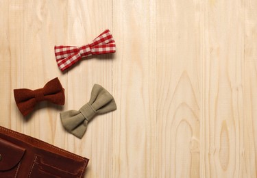 Photo of Stylish color bow ties and wallet on wooden table, flat lay. Space for text