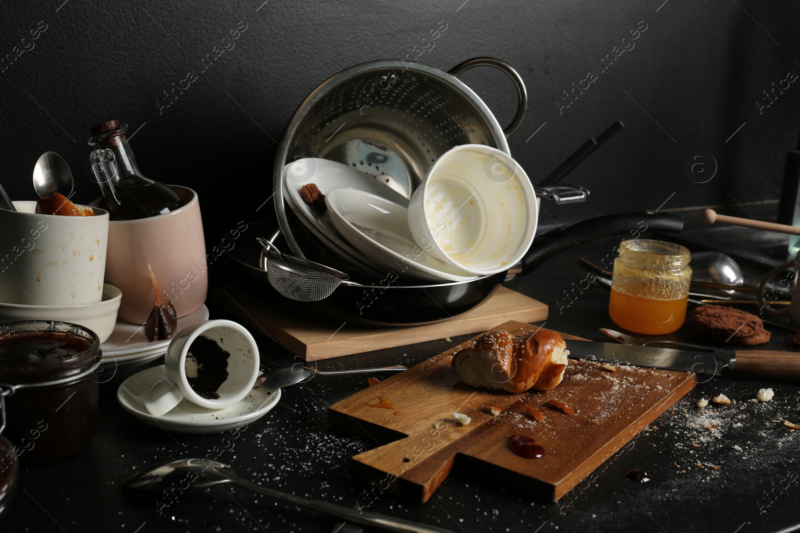 Photo of Many dirty utensils, dishware and food leftovers on black countertop. Mess in kitchen