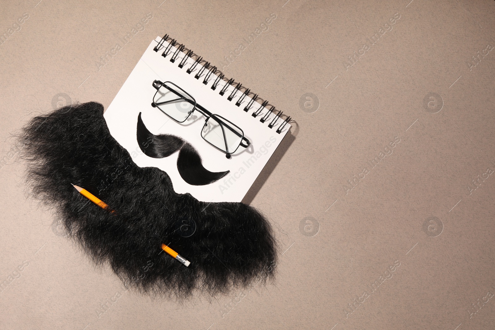 Photo of Flat lay composition with artificial moustache and glasses on light brown background, space for text