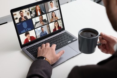 Image of Man having video chat with coworkers via laptop at white table, closeup